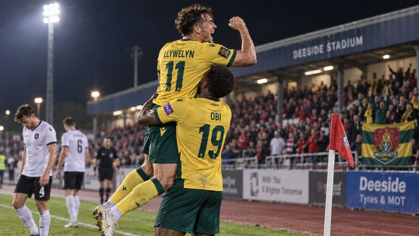 Deri Llywelyn and Efe Obi celebrate a goal by the corner flag