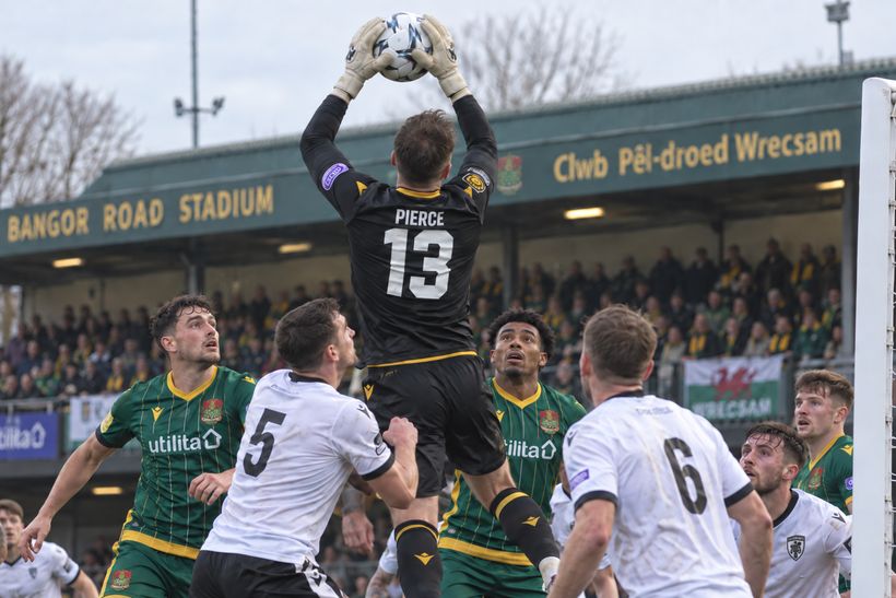 Goalkeeper Osian Pierce claims a high ball under pressure